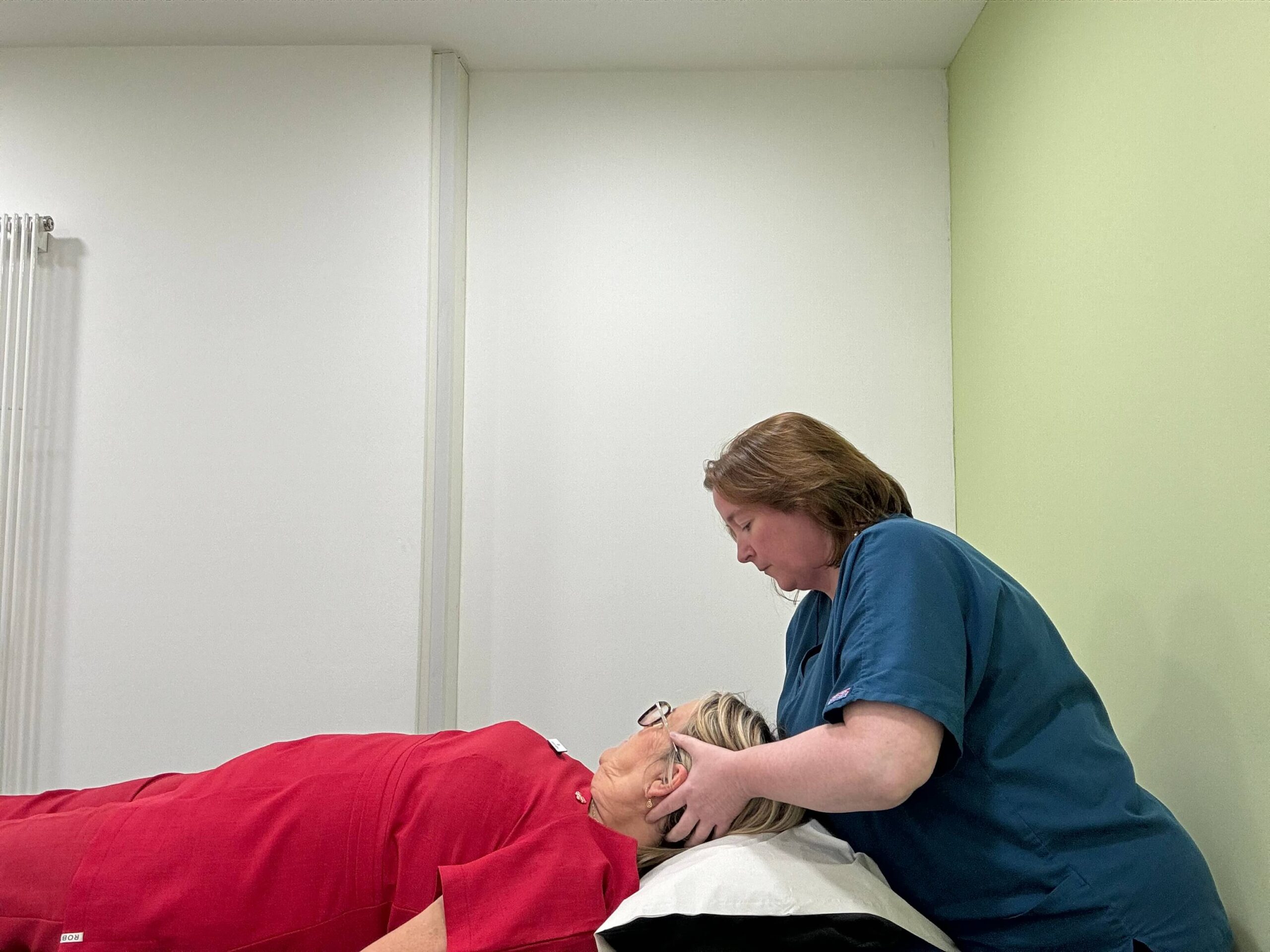 debbie osteopathy a woman in blue giving osteopathy treatment to a woman in red